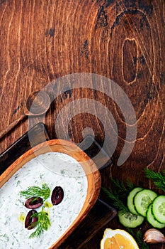 Traditional Greek sauce Tzatziki in olive wooden bowl on old rustic background.