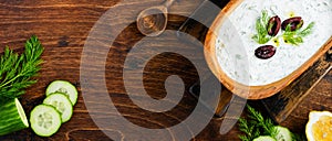 Traditional Greek sauce Tzatziki in olive wooden bowl on old rustic background. Top view