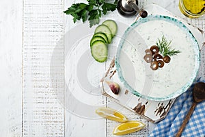 Traditional Greek sauce Tzatziki. Yogurt, cucumber, dill, garlic and salt oil in a ceramic bowl on a light wooden background.