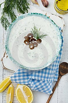 Traditional Greek sauce Tzatziki. Yogurt, cucumber, dill, garlic and salt oil in a ceramic bowl on a light wooden background.