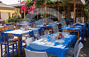 Traditional greek tavern with tables served and prepared for lunch of tourists in the summer season in Kastos island, Lefkada