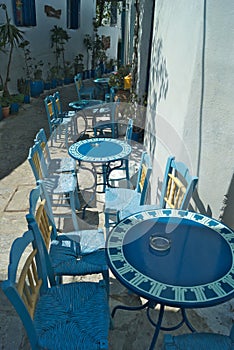 Traditional Greek taverna table and chairs in an alleyway on the charming Greek island of Amorgos.