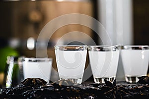 Traditional Greek vodka, known as Uzo or ouzo in shot glasses on a rustic wooden background. Space for text