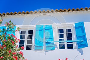 Traditional greek white house with blue window shutter and flowers in Fiskardo, Kefalonia island, Greece
