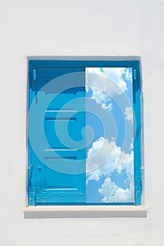 Traditional greek window against a white wall and the cloudy sky