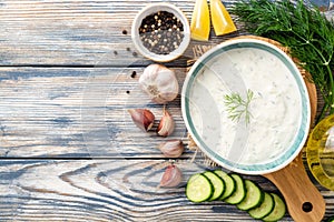 Traditional greek yogurt sauce tzatziki in bowl on wooden table