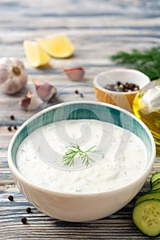 Traditional greek yogurt sauce tzatziki in bowl on wooden table