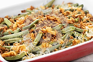 A traditional green bean casserole topped with French Fried Onions and cream of mushroom on white marble