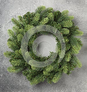 Traditional green Christmas wreath on grey concrete background.