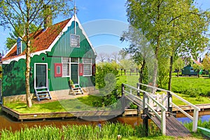 Traditional green dutch house with little wooden bridge against blue sky in the Zaanse Schans village, Netherlands. Famous tourism