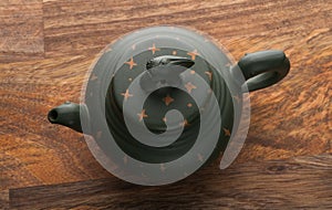 Green traditional chinese Yixin clay teapot with cicada on the cover. On the wooden table and black backround