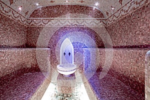 Traditional hammam sauna with modern colored lighting and stone washbasin