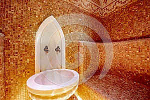 Traditional hammam sauna with modern colored lighting and stone washbasin