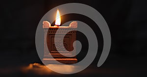 A traditional hand-made oil lamp is lit with the Om symbol used in Deepavali, Maha Shivaratri and many other religious festivals.