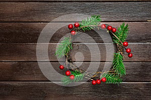 Traditional Handmade Christmas Wreath Green Fir Tree Branches Twigs Holly Berries on Dark Plank Wood Background. Top View