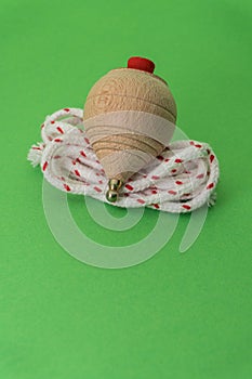 Traditional handmade wooden toy with metal tip and cord to launch the white and red spinning top.