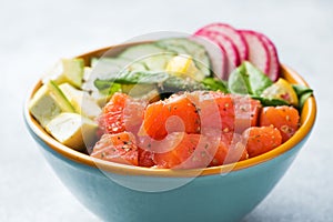 Traditional Hawaiian Poke salad with salmon, avocado rice and vegetables in a bowl