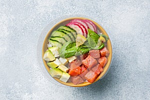 Traditional Hawaiian Poke salad with salmon, avocado rice and vegetables in a bowl. Top view