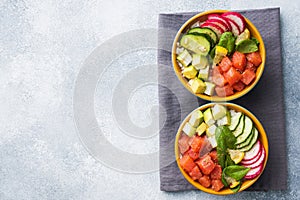 Traditional Hawaiian Poke salad with salmon, avocado rice and vegetables in a bowl on two persons. Top view Copy space