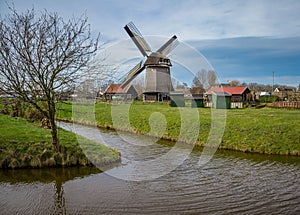 Traditional Holland farm with a working windmill near a stream