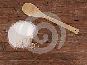 Traditional home made jam making equipment, wooden spoon and wax paper and cellophane covers. On wooden background.