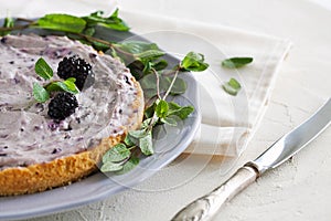 Traditional homemade blackberry tart with creamy mascarpone filling decorated with fresh mint leaves on white background