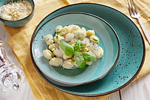 Traditional homemade cooked italian potato gnocchi with butter, parsley and parmesan cheese on white wooden background