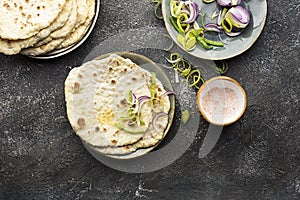 Traditional homemade flat breads for a snack with fresh seasonal vegetables, herbs and yoghurt sauce with olive oil and