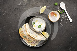 Traditional homemade flat breads for a snack with fresh seasonal vegetables, herbs and yoghurt sauce with olive oil and