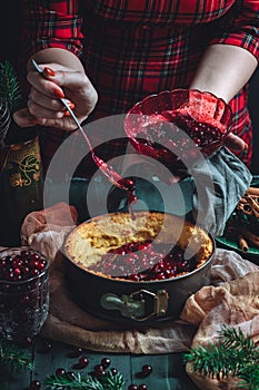Traditional homemade french cake with cranberries served on green wooden table, cooking process.