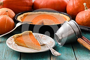 Traditional homemade pumpkin pie on white plate surrounded with