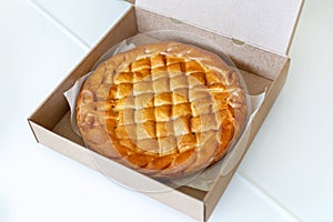 Traditional homemade rustic baked pie with seasonal fruit or meat filling in cardboard box  on white. Fast food to go.