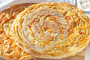 Traditional homemade Tajik Fatir (layered flat bread) with cheese and onion on light wooden background