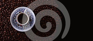 Traditional hot coffee cup with beans over a black background.