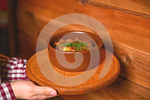 Traditional hot goulash soup. Waiter serving vegetable stew in a pot. Concept for a tasty meal. Restaurant service.