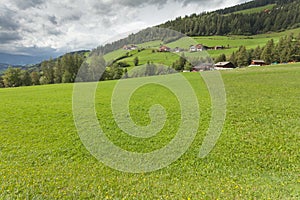 Traditional houses in a cloudy mornig surrounded by green pasture