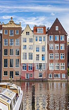 Traditional houses and a cruiseboat at the Damrak in Amsterdam