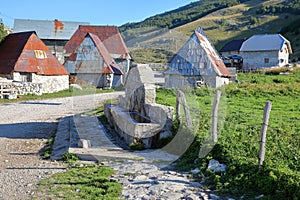 Traditional houses in Lukomir village, with a fountain in the foreground