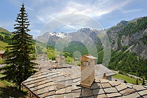 Traditional houses roofs and chimneys, with a mountain range in the background, Saint Veran