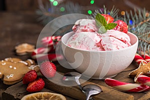 Traditional ice cream served in a glass bowl. Displayed with candy canes on wooden rustic table. Sparkling Christmas tree lights b