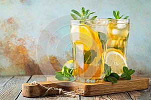 Traditional iced tea with lemon and ice in tall glasses on a wooden rustic table. With copy space