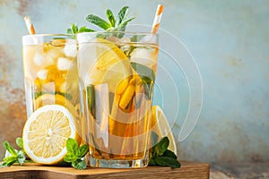 Traditional iced tea with lemon and ice in tall glasses on a wooden rustic table. With copy space