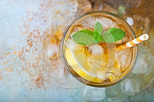 Traditional iced tea with lemon, mint and ice in tall glasses. A glass of refreshing summer drink on the old rusty background. Top