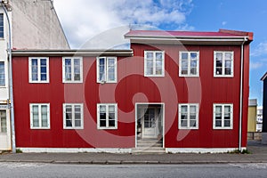 Traditional Icelandic ironclad red residential house with white window frames, clad in corrugated metal sheets in Reykjavik,