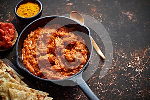Traditional Indian chicken tikka masala spicy curry meat food in cast iron pan photo