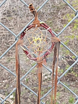 Traditional Indian dreamcatcher hanging outside on a chain  link fence