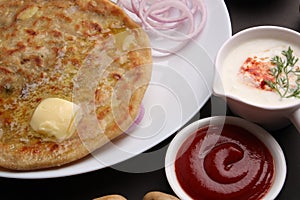 Traditional Indian food Aloo paratha or potato stuffed flat bread. served with pickle