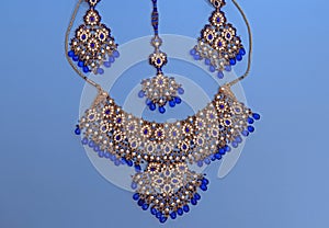Traditional Indian jewelry is gold with blue gems. Necklace, earrings, tika