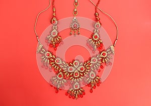 Traditional Indian jewelry is gold with red gems. Necklace, earrings, tika