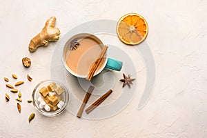 Traditional Indian masala tea chai with milk and spices on white background with ingredients above